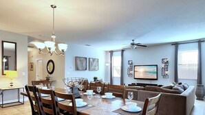 Un salon moderne comprenant un coin repas, un téléviseur et un ventilateur de plafond.