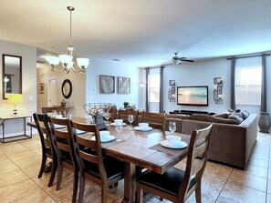 Ein modernes Wohnzimmer mit Essbereich, Fernseher und Deckenventilator.