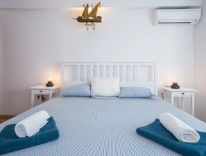 A neatly made bed with striped bedding, two bedside lamps, a white headboard, and a wall-mounted ship model. - Villa Lapis Vis - Treat yourself with the vacation you deserve! (Rukavac)