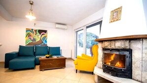 A living room with a sofa, armchair, fireplace, and artwork on the wall. - Villa Lapis Vis - Treat yourself with the vacation you deserve! (Rukavac)