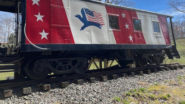 A stationary train car with a red and white color scheme, stars, and an eagle emblem.