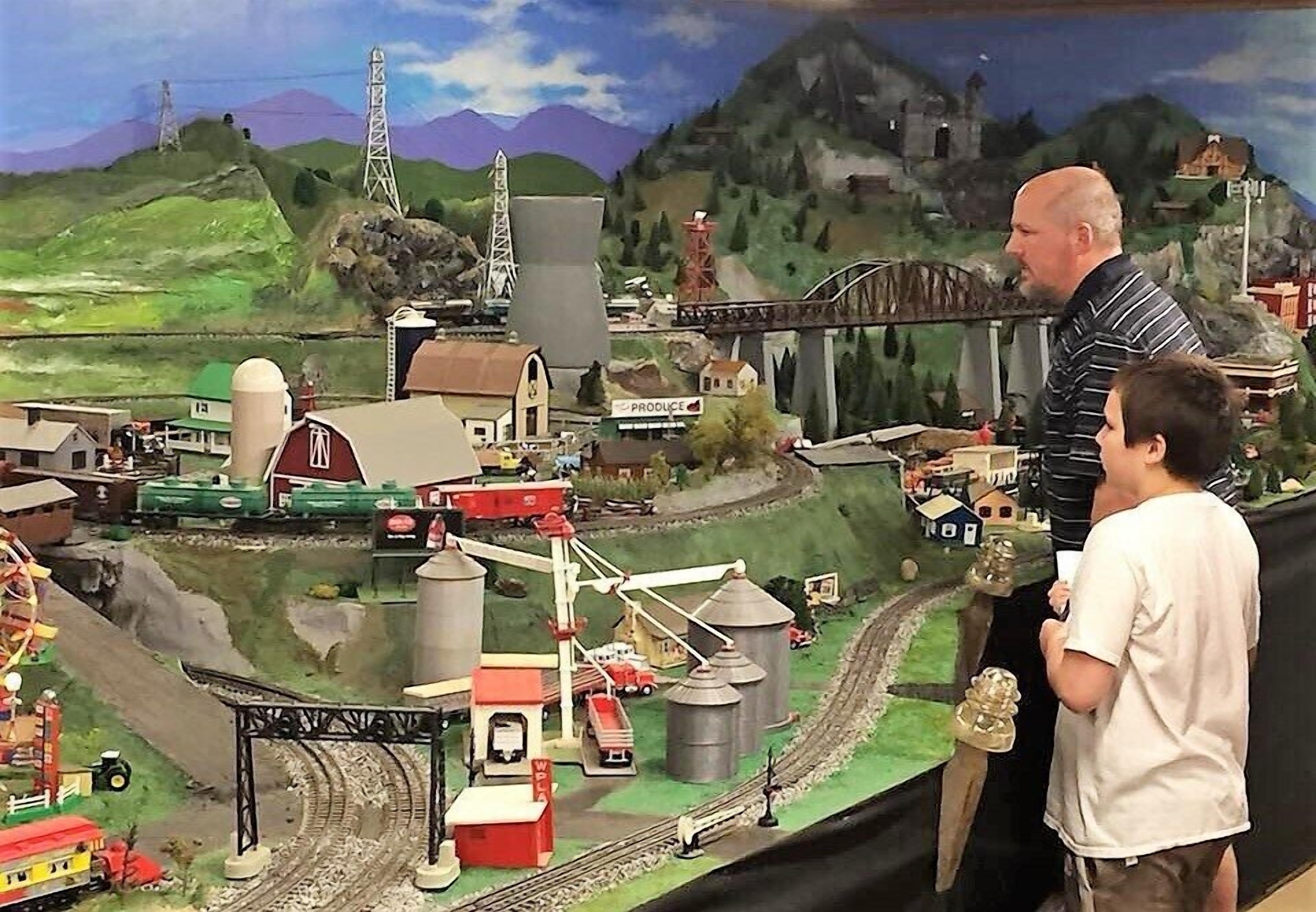 A model train setup with a bridge, buildings, and a landscape.