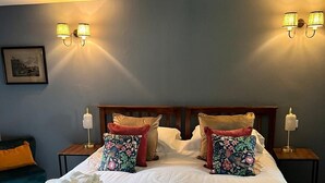 Una cama grande con ropa de cama blanca, dos mesitas de noche con lámparas y un cabecero de madera.