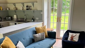Una sala de estar moderna con un sofá azul, un sillón oscuro y una alfombra estampada.