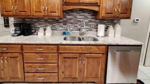 A kitchen with wooden cabinets, a granite countertop, a stainless steel sink, and a dishwasher.