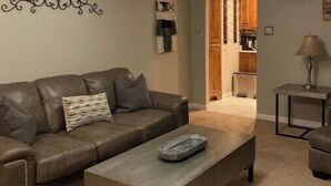 A living room with a brown leather sofa, a grey coffee table, and a ceiling fan.
