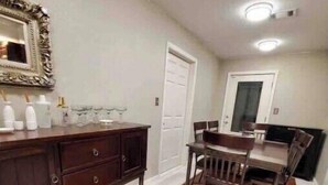 A dining area with a wooden table and chairs, a dark wooden cabinet, and a white door.