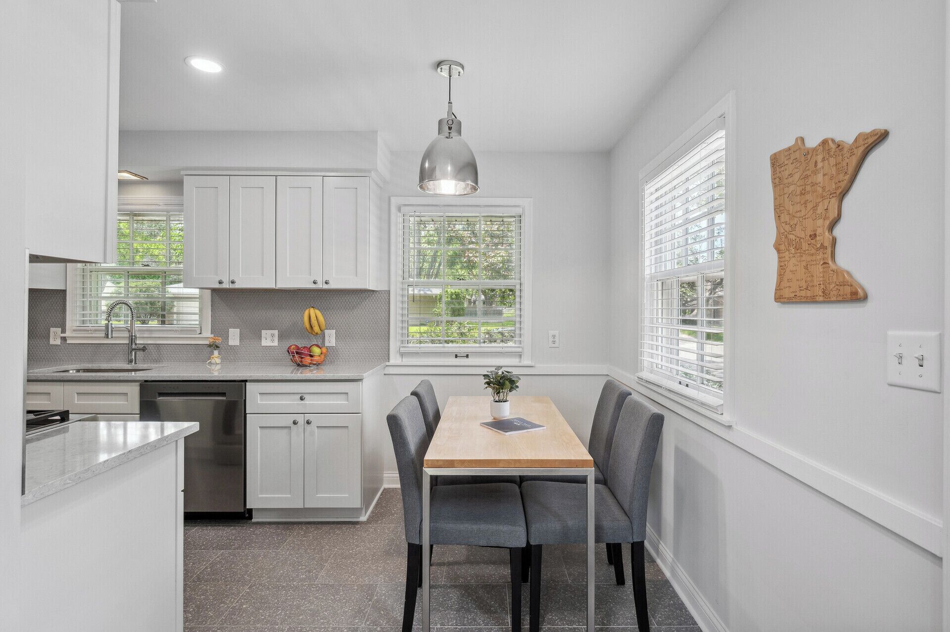 A modern kitchen with white cabinetry, a central island, and a dining area with a table and chairs.