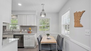 A modern kitchen with white cabinetry, a central island, and a dining area with a table and chairs. - MSP/Mall of America/Pond View with garden oasis (Richfield)