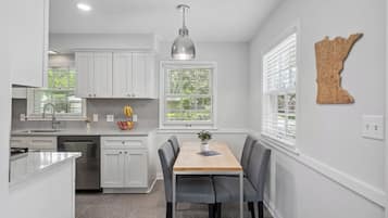 A modern kitchen with white cabinetry, a central island, and a dining area with a table and chairs.