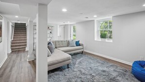 A spacious living room with a grey sectional sofa, a blue bean bag, a grey shag rug, and a large window with a view of greenery. - MSP/Mall of America/Pond View with garden oasis (Richfield)