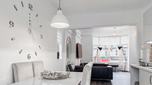 A modern kitchen with a dining area, a large clock on the wall, and a view of the street through the window. - Discover a spacious holiday home in Paignton, Devon, accommodating ten guests. (Paignton)