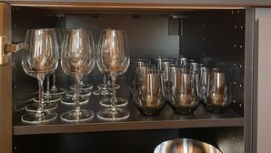 Cozinha com painel decorado com paisagem urbana, conjunto de facas, copos de vinho e uma tigela de metal.