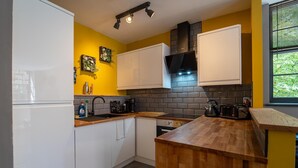 A compact kitchen with white cabinets, a black range hood, and a wooden countertop. - Stunning Modern City Centre Apartment Retreat (Nottingham)