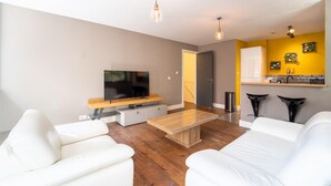A modern living room with a flat-screen TV, white sofas, a wooden coffee table, and pendant lighting. - Stunning Modern City Centre Apartment Retreat (Nottingham)
