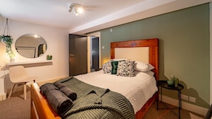 A bedroom with a bed, a bedside table, a chair, a mirror, and a door. - Stunning Modern City Centre Apartment Retreat (Nottingham)