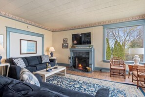A living room with a fireplace, a sofa, a coffee table, and a large window.