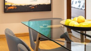 Un comedor moderno con una mesa de vidrio, sillas azules y un cuadro abstracto grande en la pared.