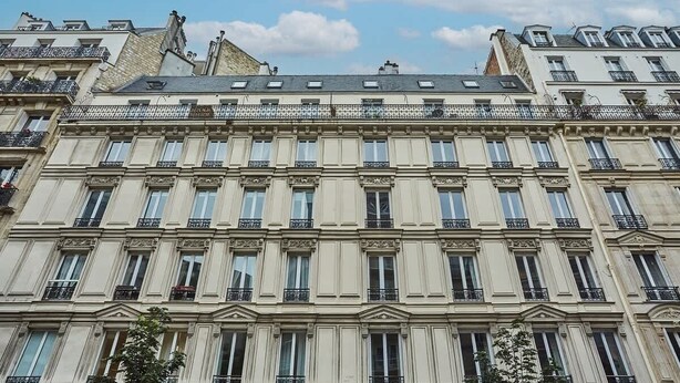 A multi-story building with a classical architectural style, featuring symmetrical windows and ornate balconies. - Charming Apartment - Eiffel Tower/Trocadero (Paris)