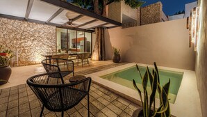 A patio with chairs, a table, a pool, and a stone wall. - Casa Balada Santa Lucia, with Parking by Cercana (Mérida)