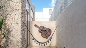 A stone wall, a hammock with a guitar, a small pool, and potted plants. - Casa Balada Santa Lucia, with Parking by Cercana (Mérida)