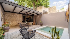 A pool area with chairs and a table, surrounded by stone walls and potted plants. - Casa Balada Santa Lucia, with Parking by Cercana (Mérida)