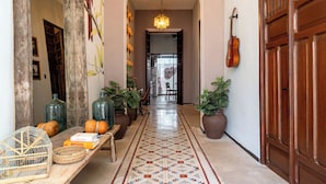 A hallway with a patterned floor, a wooden door, a hanging guitar, and a mirror with wall art. - Casa Balada Santa Lucia, with Parking by Cercana (Mérida)