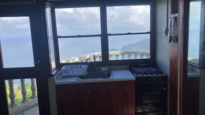 A small kitchen with a view of the sea, a gas stove, and a sink.