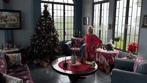 A cozy living room with a Christmas tree, a dining table with a placemat, and a sofa.
