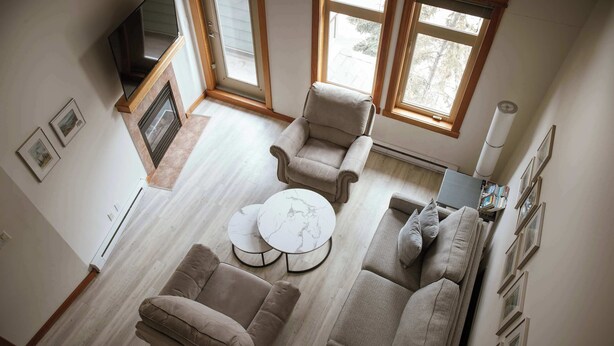 Ein geräumiges Wohnzimmer mit einer Sofagarnitur, einem Couchtisch und einem an der Wand befestigten Fernseher.