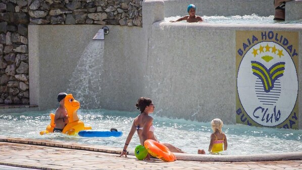 Una piscina con un muro de piedra y un cartel que dice "Baia Holiday Club".