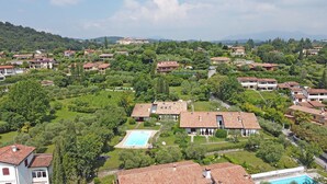Quartiere residenziale con case, piscina e vegetazione rigogliosa.