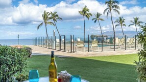 Vista de la playa con palmeras, sillas de descanso y una mesa con bebidas.