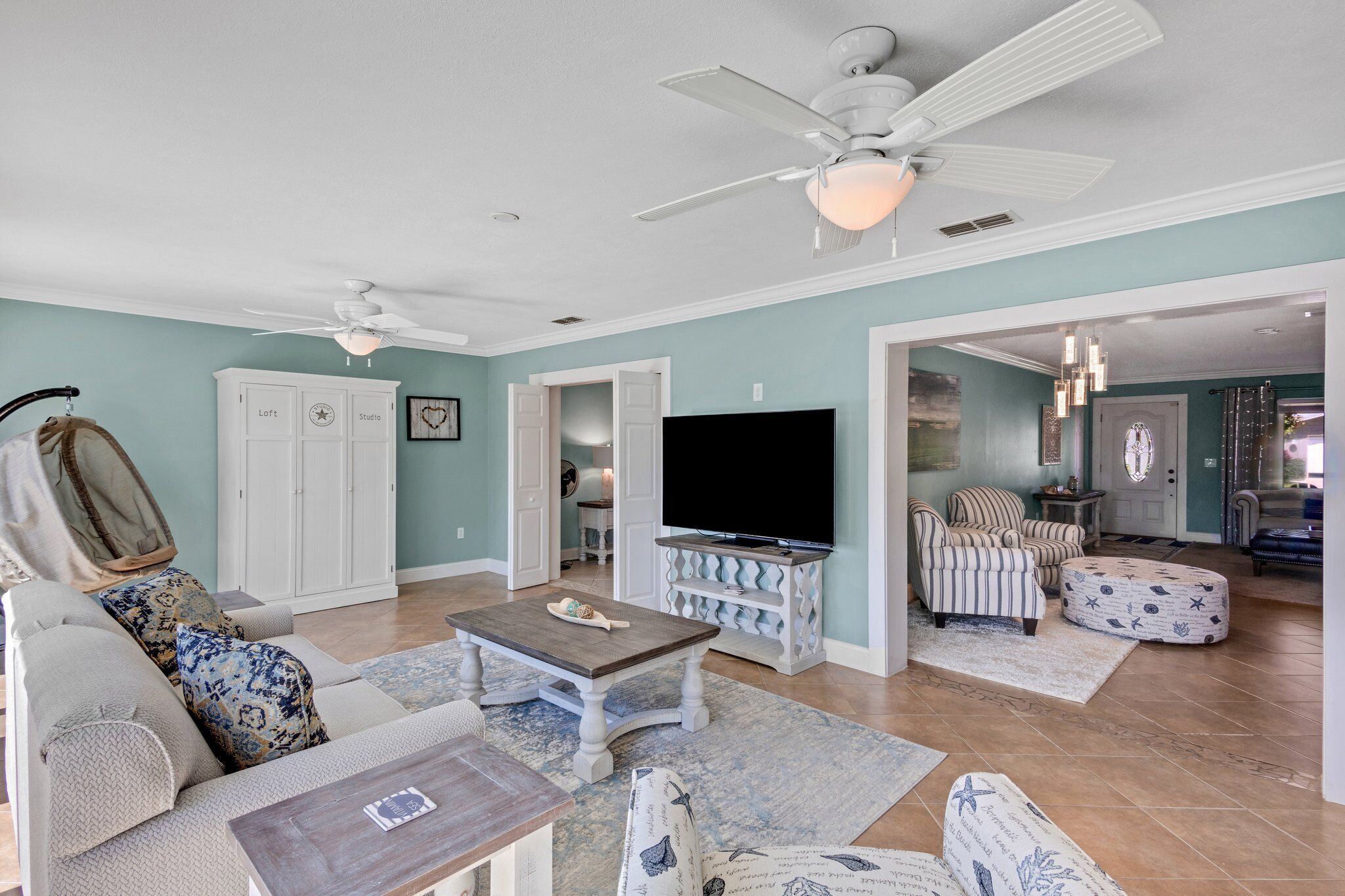 A spacious living room with a ceiling fan, a flat-screen TV, and a comfortable seating area.