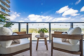 Un balcon avec deux chaises en bois, une petite table ronde et un pot de fleurs.
