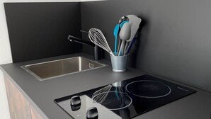 Een moderne keuken met een zwart aanrecht, een roestvrijstalen spoelbak en een inbouw inductiekookplaat.