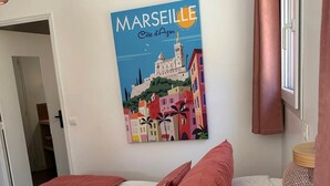 A bedroom with a bed, a wall-mounted poster of a cityscape, and a window with curtains. - 3.juju (CASSIS)
