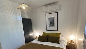 A modern bedroom with a large bed, a hanging light fixture, a framed picture on the wall, and a wooden floor. - 3.jacko (CASSIS)