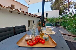 A table set with tomatoes, garlic, a bottle of olive oil, and a hat. - 3.jacko (CASSIS)