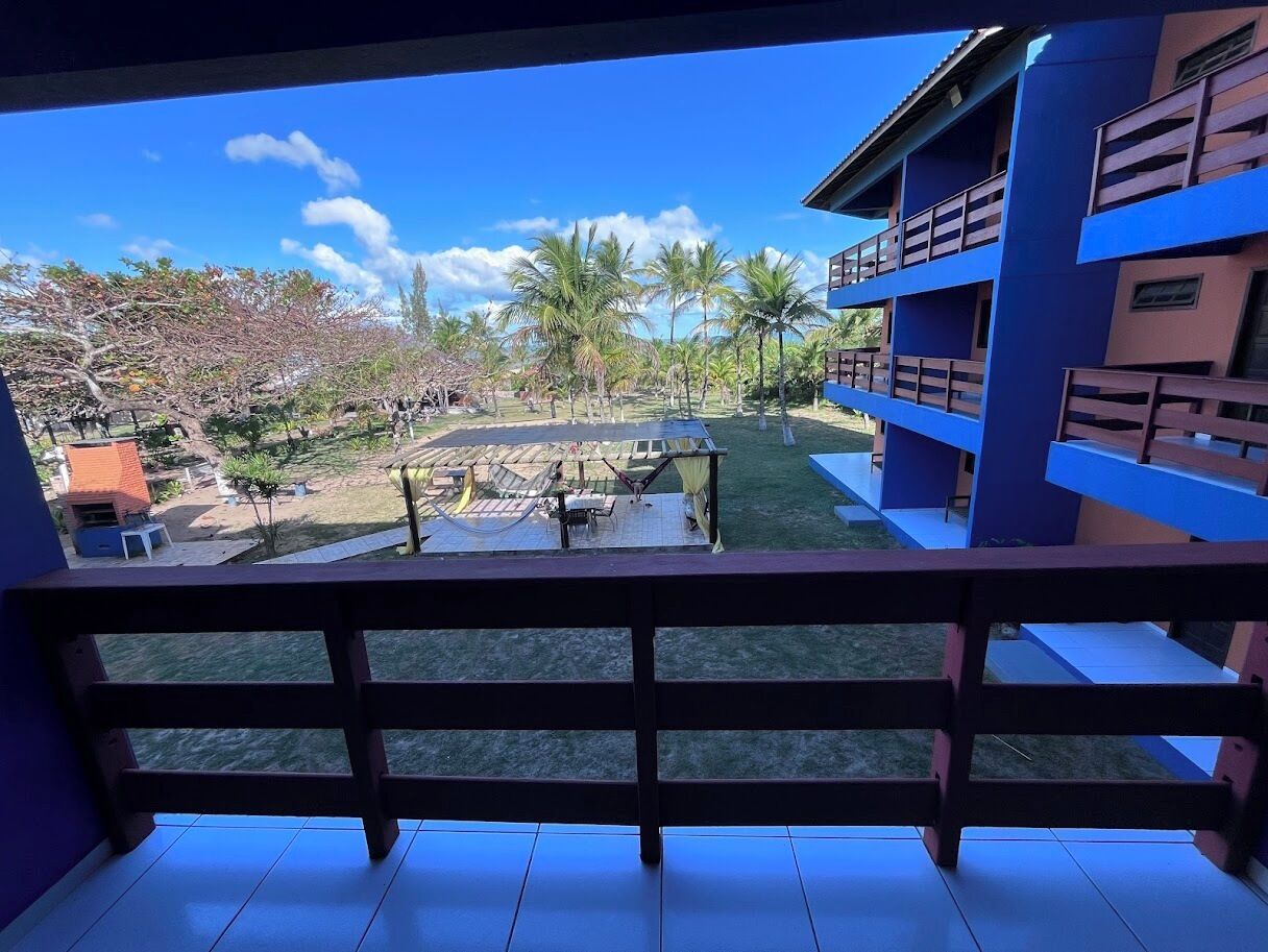 A balcony with a view of a courtyard, including a pool and palm trees.