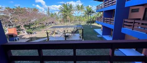 A balcony with a view of a courtyard, including a pool and palm trees.