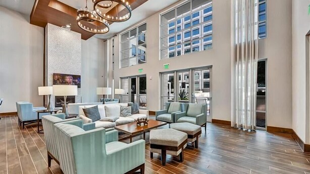 A spacious lobby with a high ceiling, large windows, and a modern chandelier.