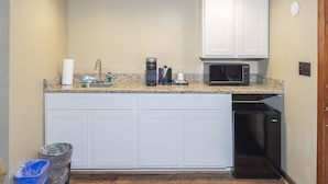 A compact kitchen with white cabinets, a granite countertop, a coffee maker, a microwave, and a dishwasher. - Perfect Moment Cottage (Blowing Rock)