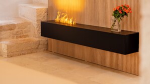 A modern interior with a fireplace, a flat-screen TV mounted on a wooden wall, and a staircase with a handrail.
