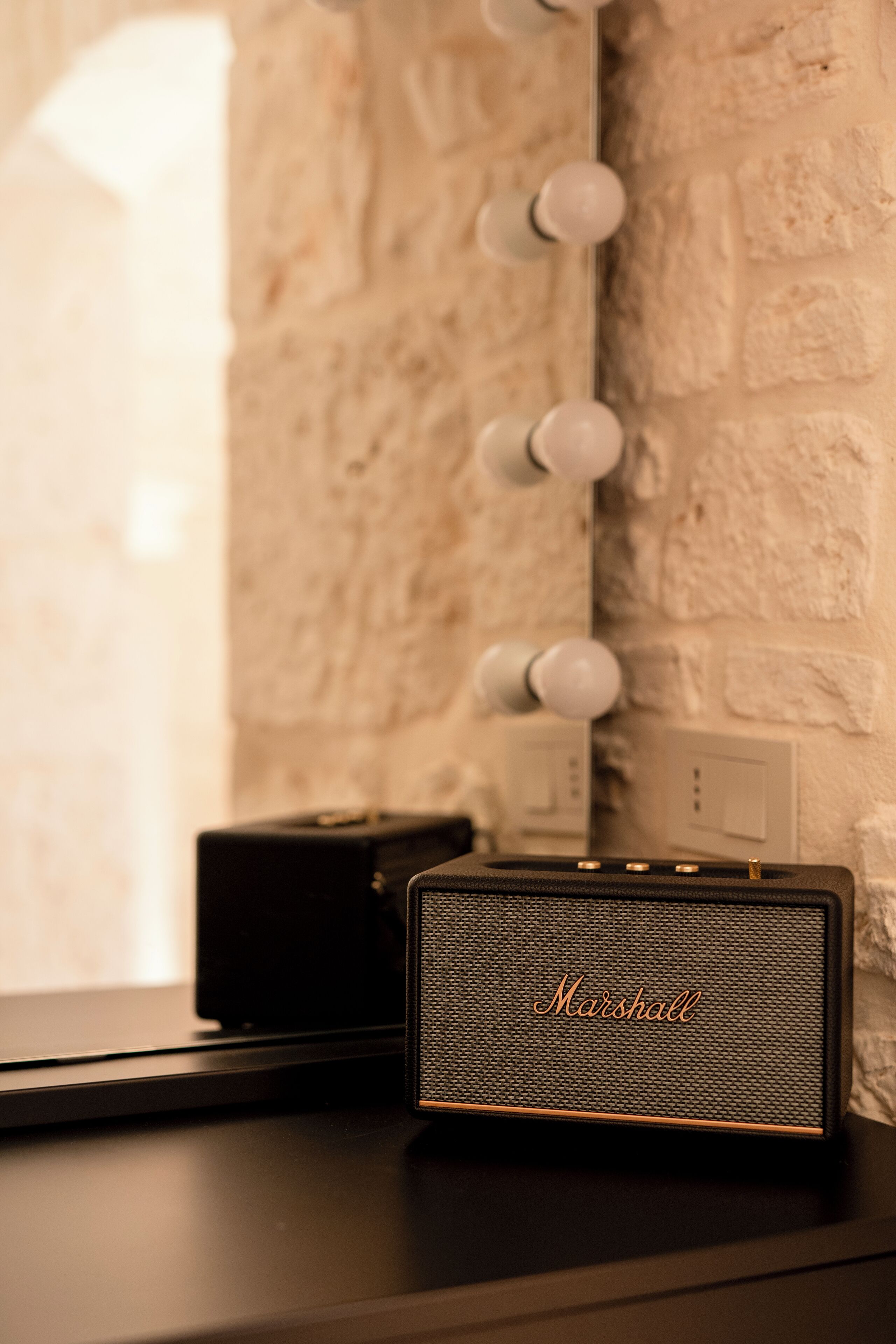 Een Marshall speaker op een donker oppervlak, met een bakstenen muur op de achtergrond.