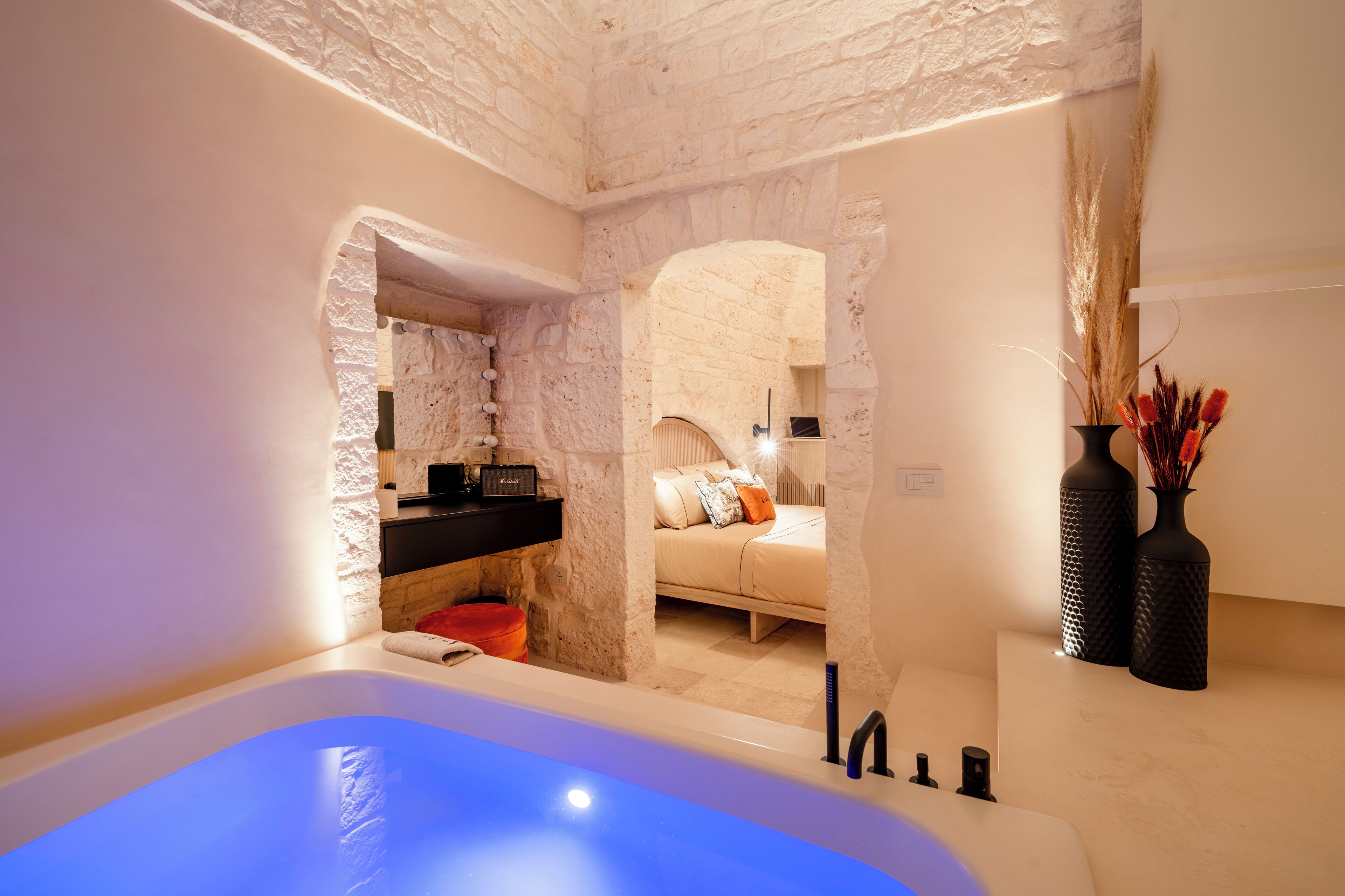 A modern bathroom with a bathtub, a vanity with a mirror, and a bed with pillows.