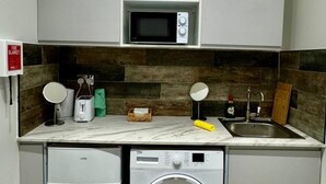Une cuisine compacte équipée d’un four à micro-ondes, d’un grille-pain et d’un lave-linge.
