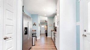 A narrow hallway with wooden flooring, white walls, and a ceiling fan. - Deltaville 2BR Retreat, Walk to Museum, Boat Parking (Deltaville)