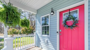 A porch with a white railing, a red door, and a wreath hanging on the door. - Deltaville 2BR Retreat, Walk to Museum, Boat Parking (Deltaville)