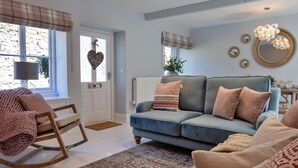 Un salon chaleureux avec un canapé bleu, un fauteuil à bascule et un tapis à motifs.